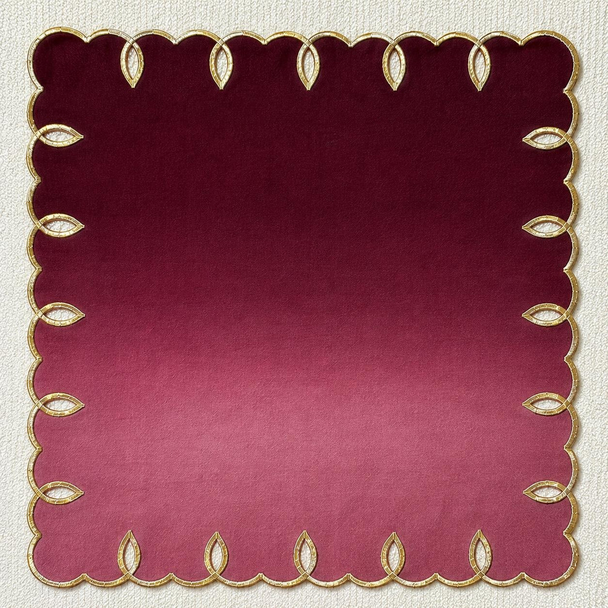 Foglia embroidered linen napkin in Burgundy, flat on a neutral backdrop
