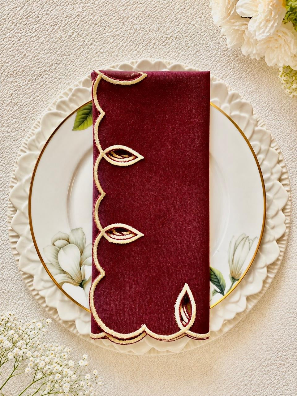 Foglia embroidered napkin folded on a gold-rimmed plate